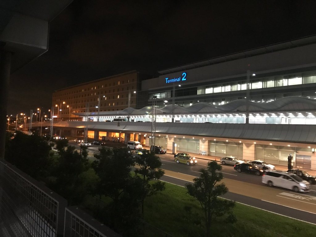 Haneda Airport Terminal 2 building lit up at night with taxis in front