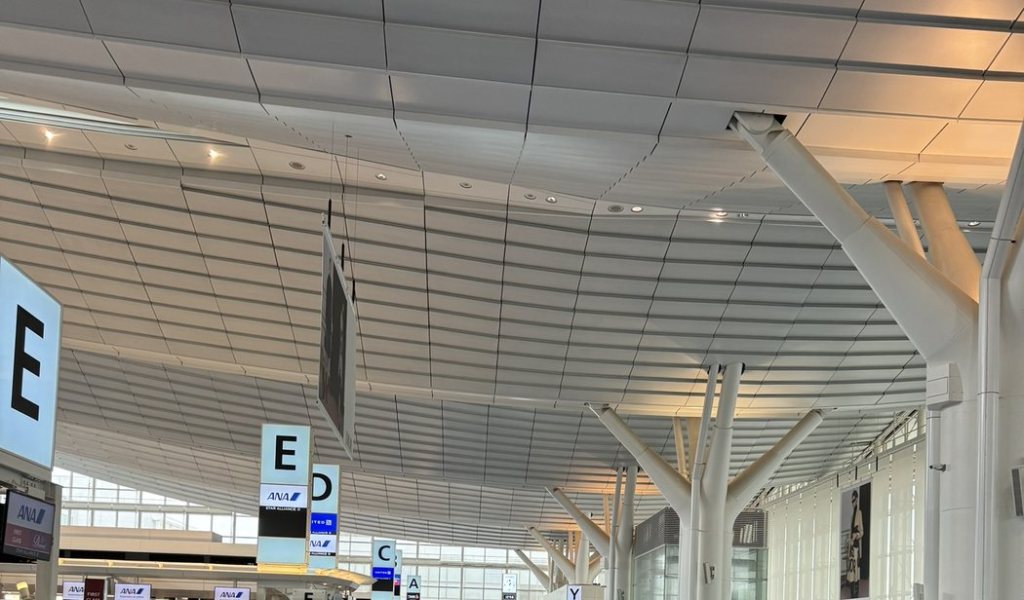 The high curved ceiling and airline check-in signs of the departures hall at Haneda Airport Terminal 3