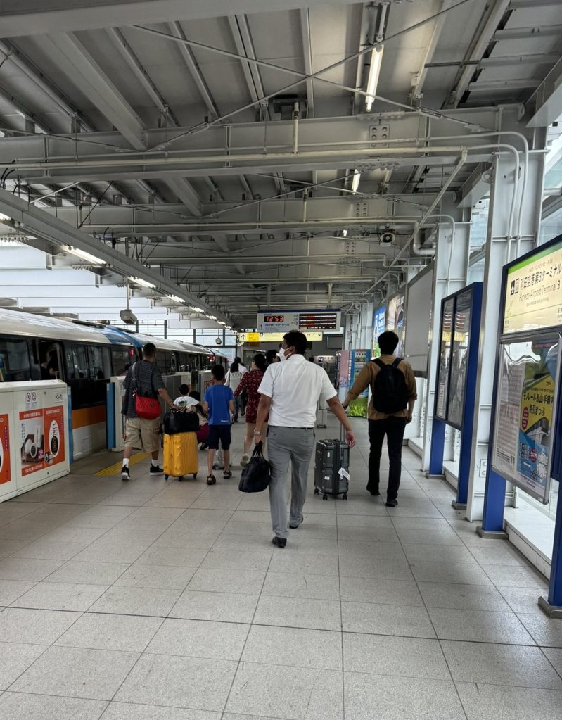 Travelers with suitcases walking along the Tokyo Monorail platform at Haneda Airport Terminal 3