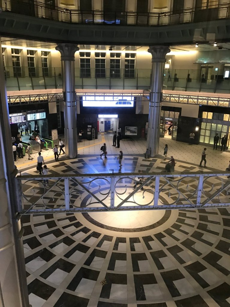 The dome hall of Tokyo Station seen from above, with a patterned marble floor and ticket gates