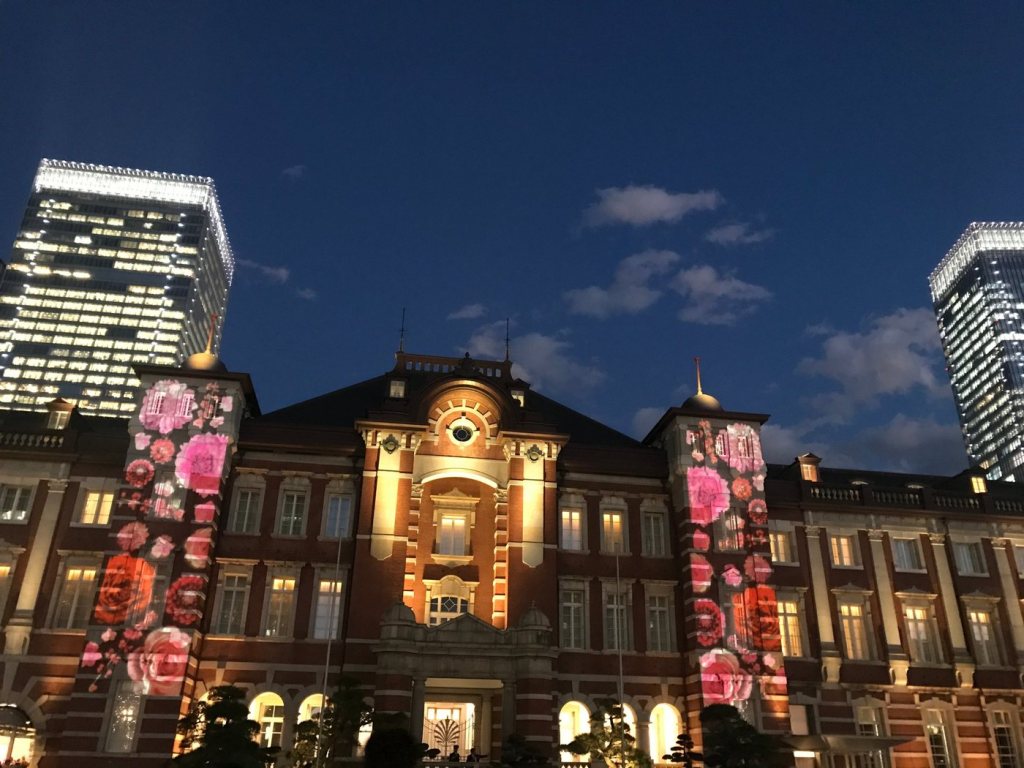 The red-brick Tokyo Station Marunouchi building lit up at night with flower images projected on its towers