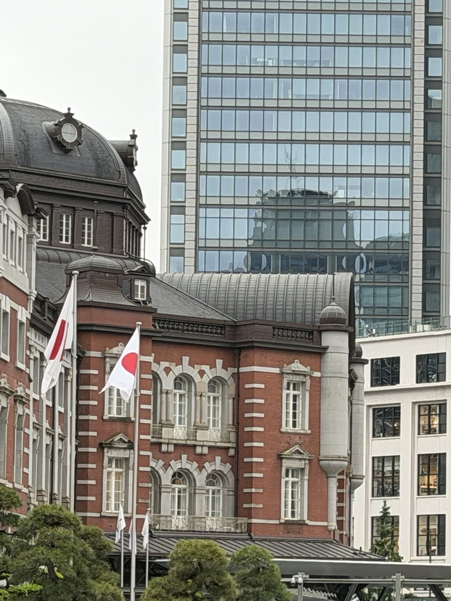 Tokyo Station Marunouchi building, red brick with Japanese flags, in front of modern glass towers